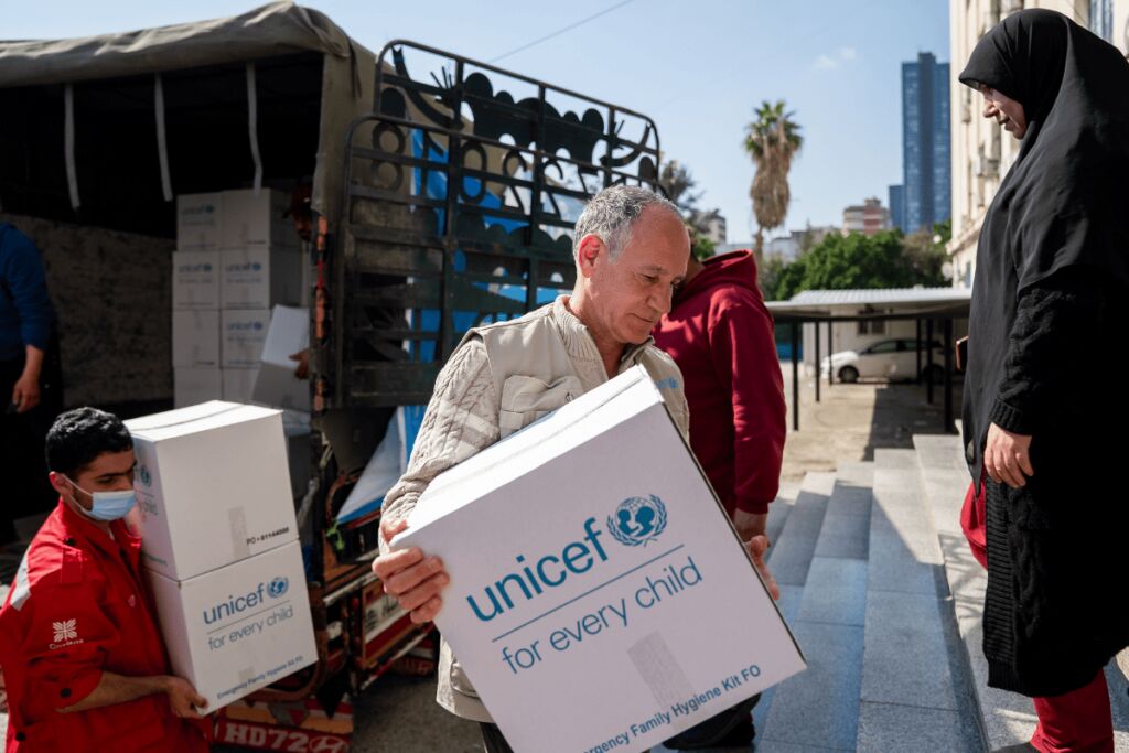 Ihmiset kantavat Libanonissa rekasta valkoisia laatikoita, joissa on UNICEFin logo. 