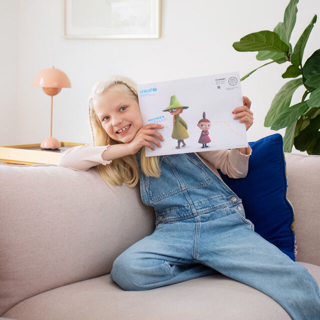 Lapsi pitelee kädessään kirjekuorta, jossa lukee "Muumien seikkailuposti".