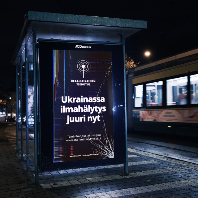 Ukrainan ilmahälytyksistä kertova kampanja digitaalisella ulkonäytöllä raitiovaunupysäkillä Helsingissä