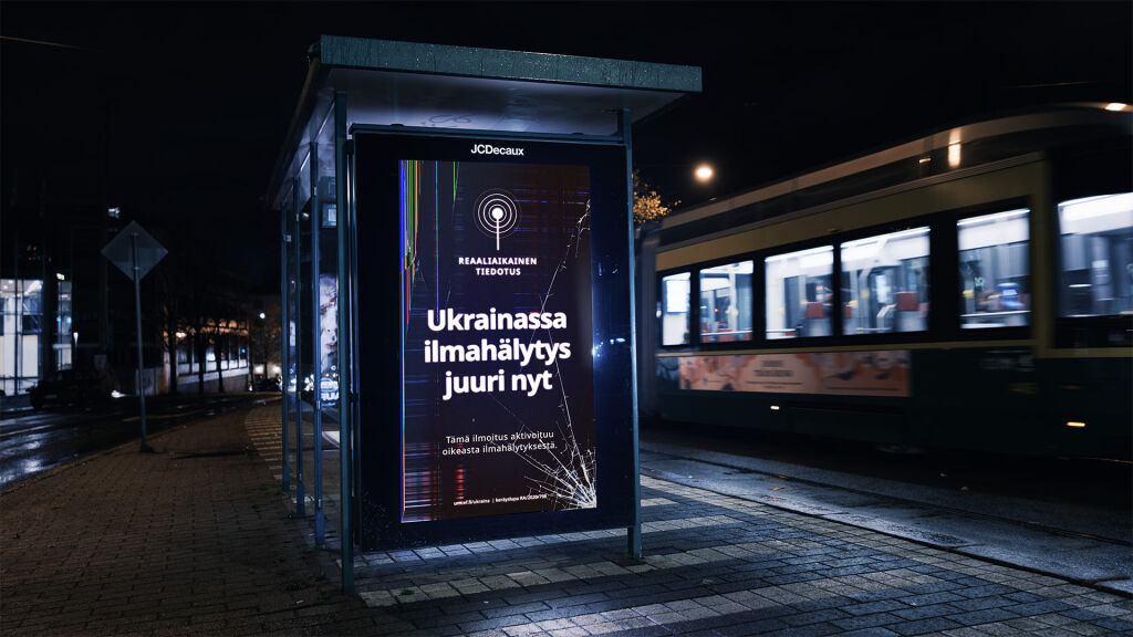Ukrainan ilmahälytyksistä kertova kampanja digitaalisella ulkonäytöllä raitiovaunupysäkillä Helsingissä
