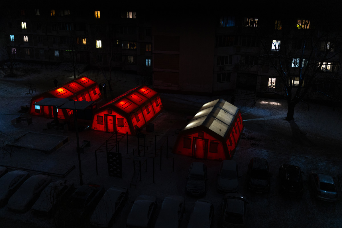 Oranssi teltta keskellä pimeää kaupunkimaisemaa Ukrainassa.