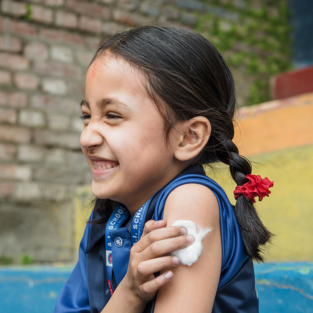 Barnet ler trots att hon precis fått vaccinet på axeln. Genom UNICEF levereras hjälpen tillförlitligt.