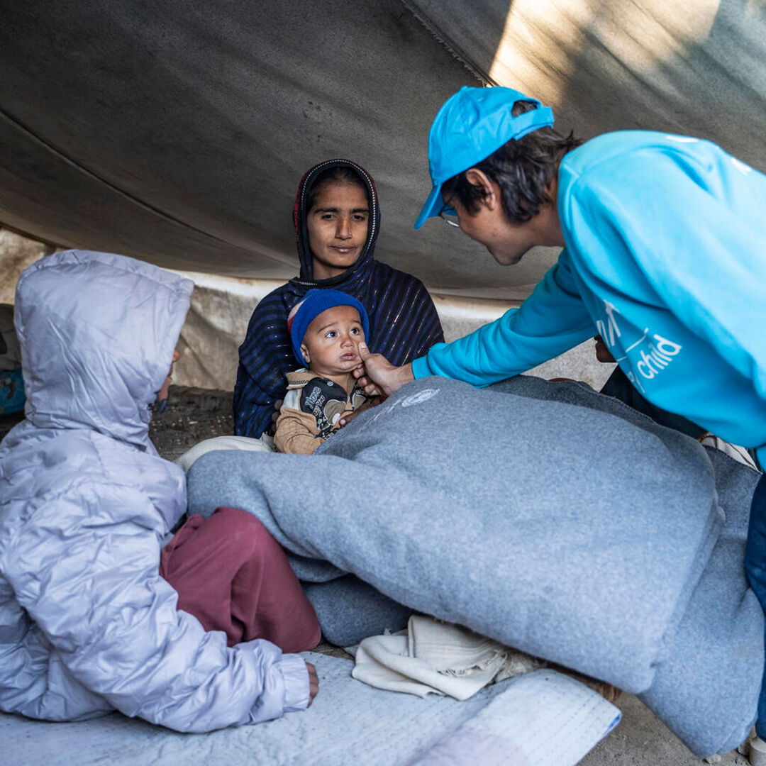 Pakistanissa UNICEFin työntekijä on toimittanut perheelle lämpimiä talvi huopia. Hän koskettaa lapsen poskea. 