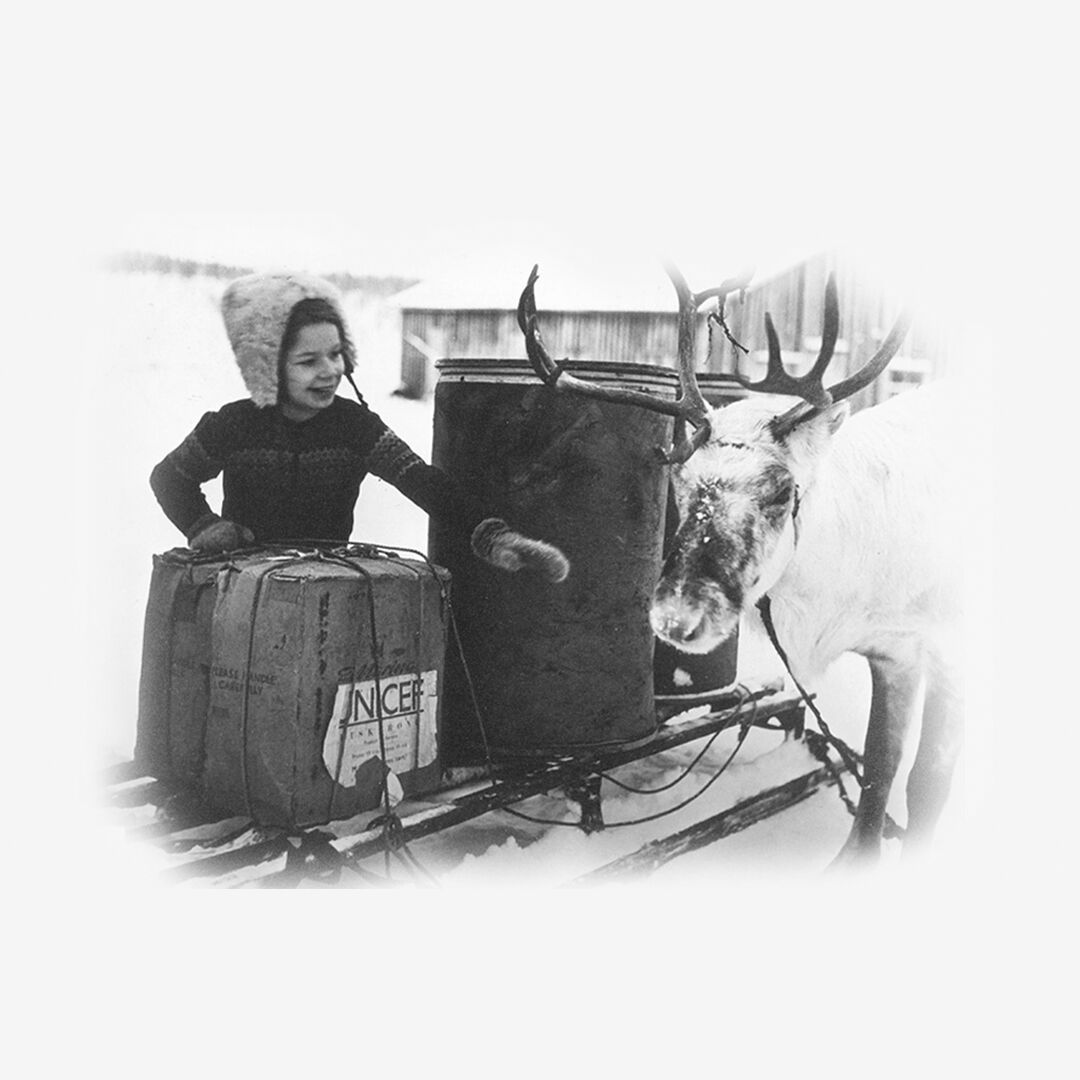 Suomalainen lapsi tervehtii poroa, joka toi UNICEFin paketin.