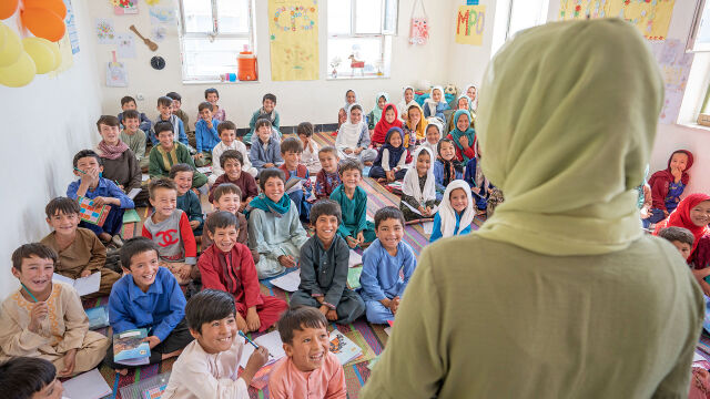 Kaksi miestä lastaa laatikoita, joissa lukee UNICEF isossa varastossa.