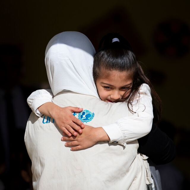 UNICEFin liiviä pitävä työntekijä kantaa lasta. 