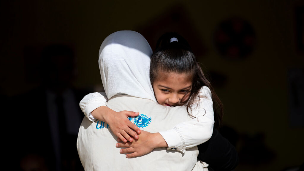 UNICEFin liiviä pitävä työntekijä kantaa lasta. 