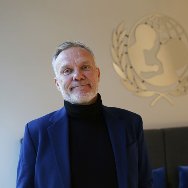 Bo Viktor Nulund Suomen UNICEFin toimistolla UNICEFin logo taustalla. 
