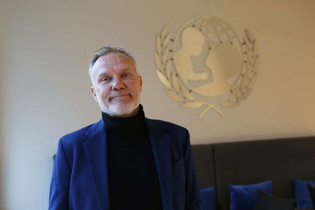 Bo Viktor Nulund Suomen UNICEFin toimistolla UNICEFin logo taustalla.