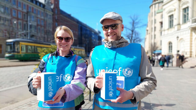 Kaksi UNICEF-vapaaehtoista keräyslippaiden kanssa.