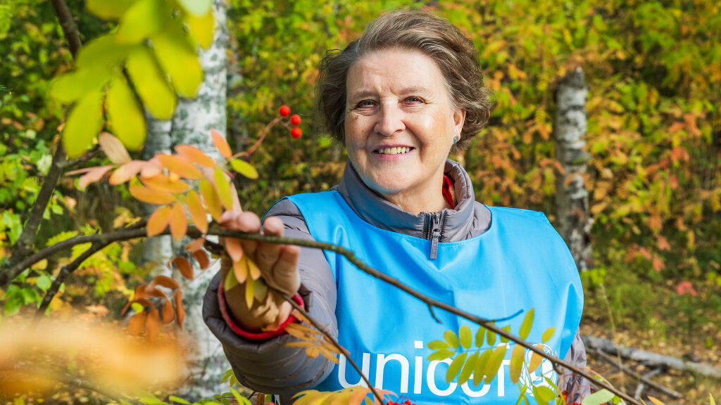 UNICEF-vapaaehtoinen kurkistaa puun takaa.