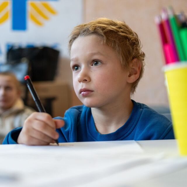 Ukrainalainen poika piirtää koululuokassa.