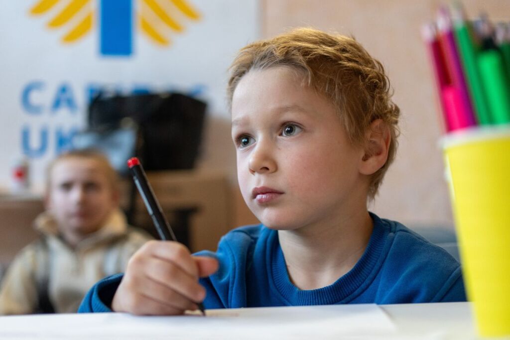 Ukrainalainen poika piirtää koululuokassa.