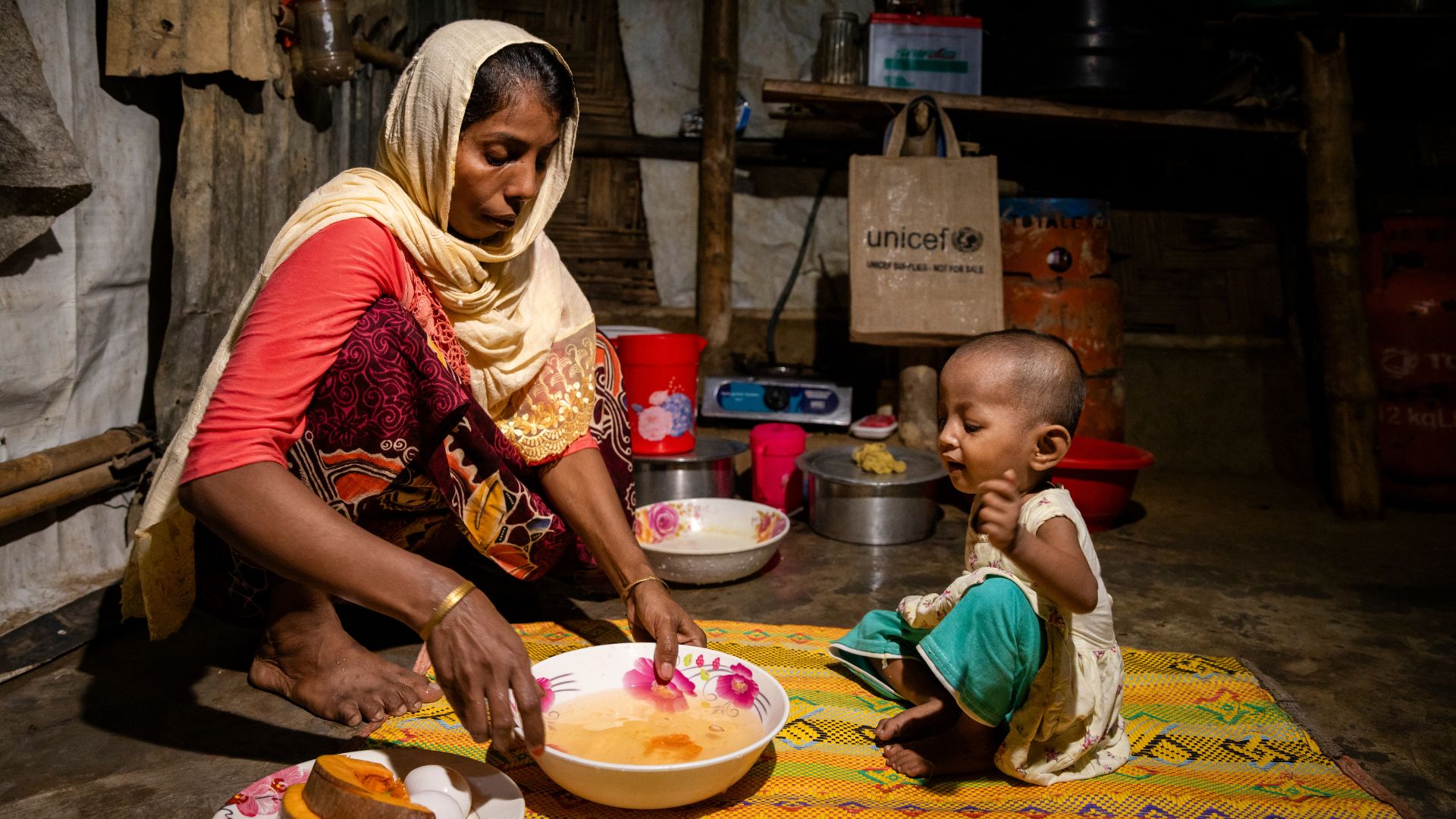 Rubeda valmistaa vakavasta aliravitsemuksesta kärsivälle Sofiba-tyttärelleen ruokaa Co'x Bazarin pakolaisleirillä Bangladeshissa.