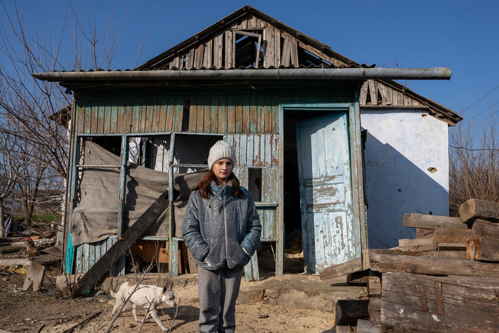 12-vuotias Alina seisoo pahoin vaurioituneen kotinsa edustalla Kobzartsin kylässä, Mykolaivissa Ukrainassa.